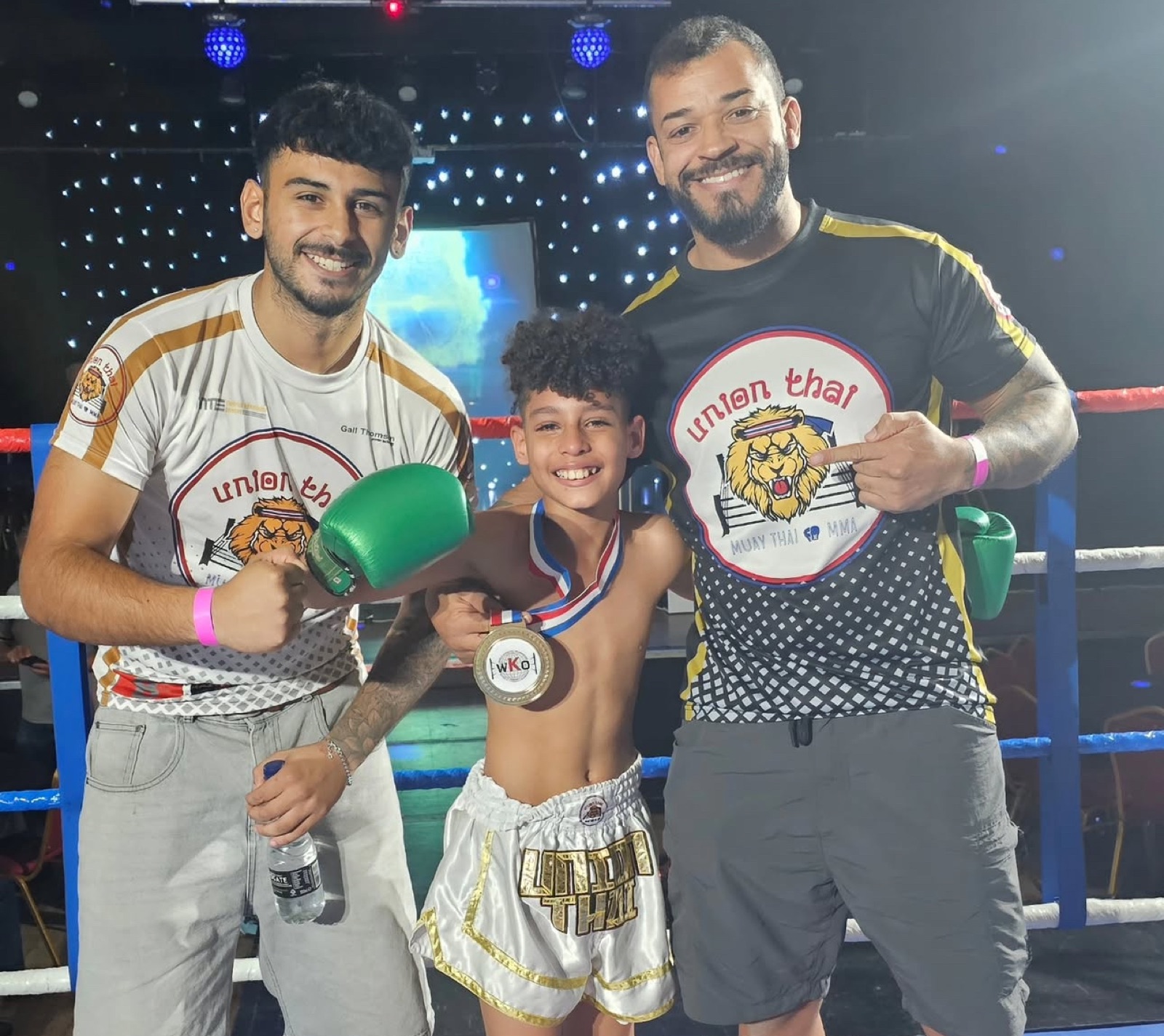 Union Thai coaches and a young fighter with his medal
